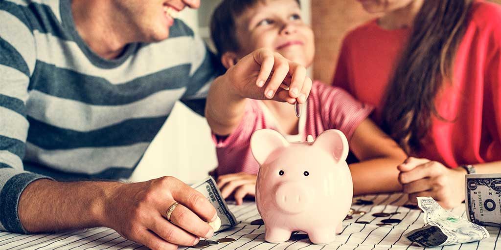 Little girl putting money in a piggy bank