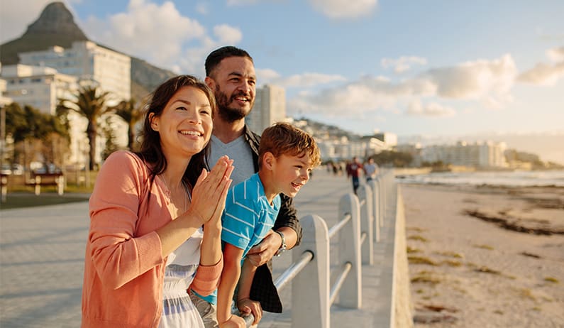 Mom, dad and son smiling and looking at beach